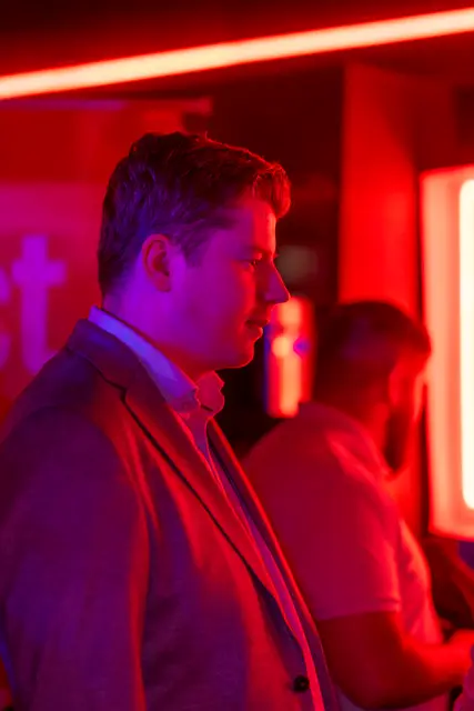 A man at a bar bathed in red light.