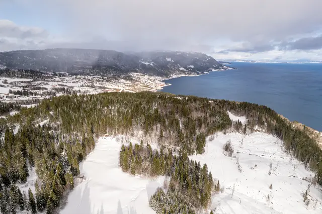 An aerial view of snow-covered forested hills in Norway.