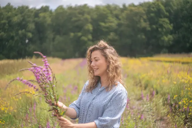 A woman holding wildflowers in a summer meadow.