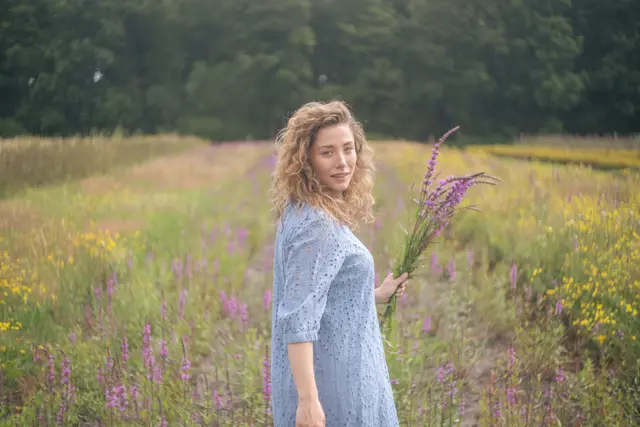 A woman holding a bunch of wildflowers in a meadow.